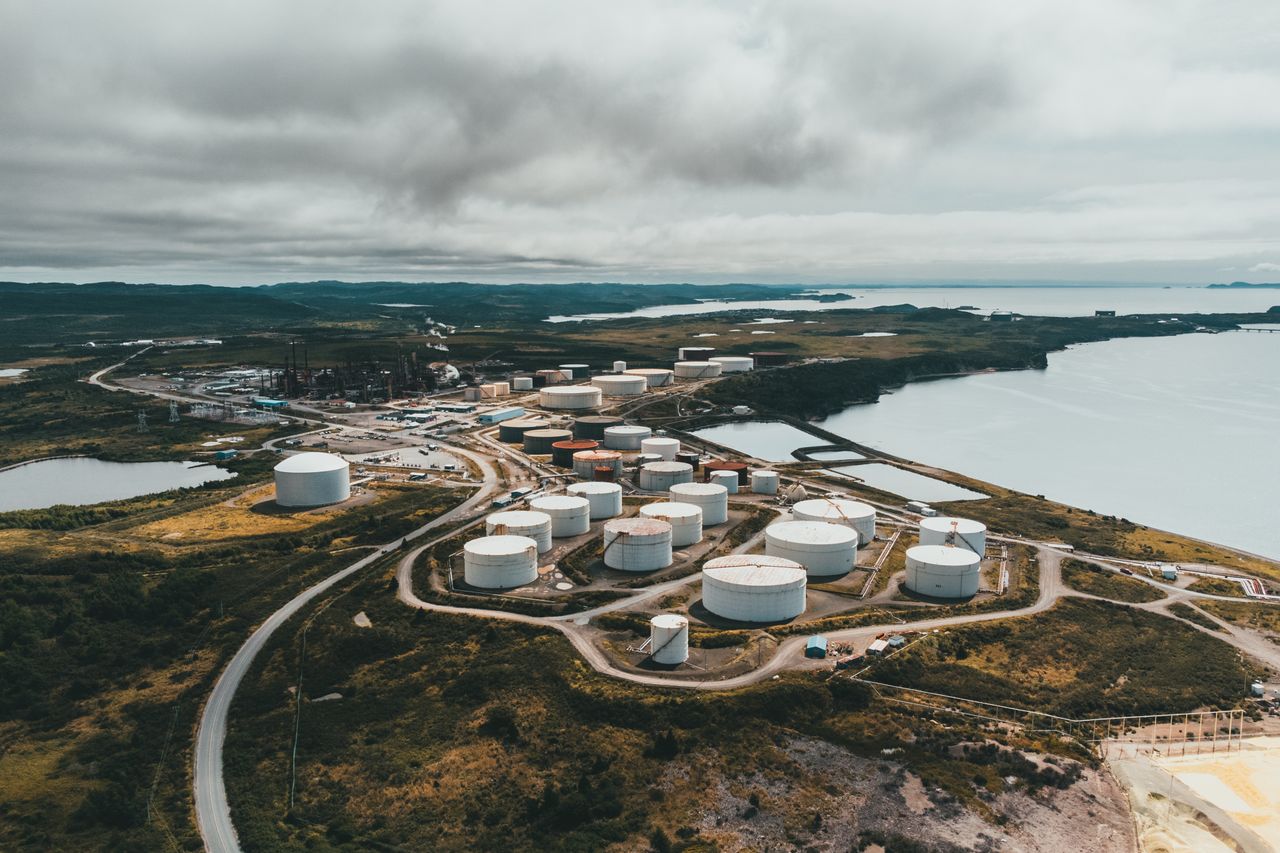 services-04 Aerial shot of industrial storage tanks near a waterfront landscape, showcasing industrial infrastructure.